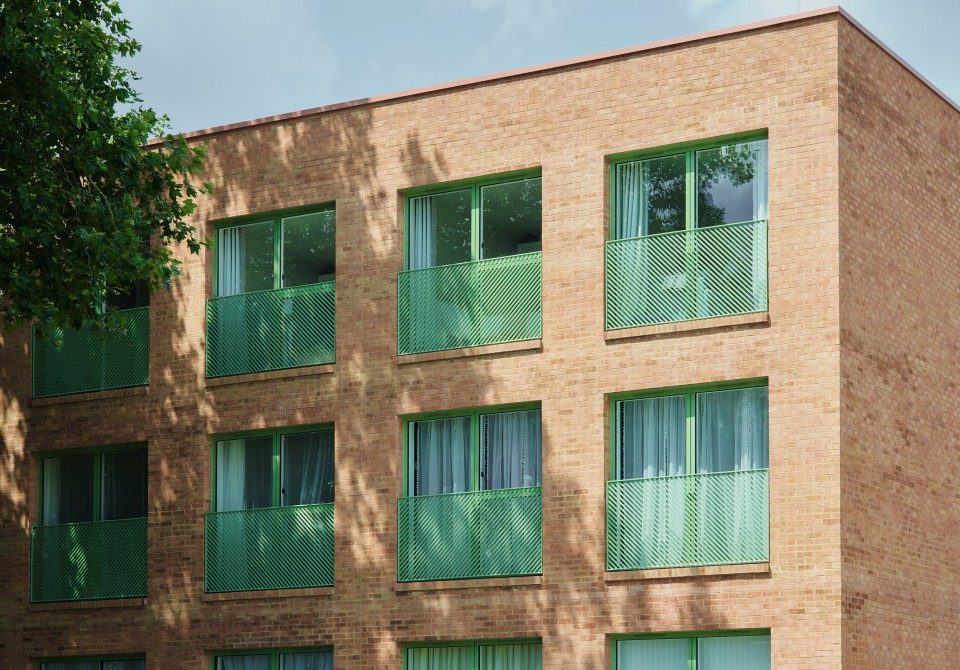 Brick building with green juliet balconies and a tree